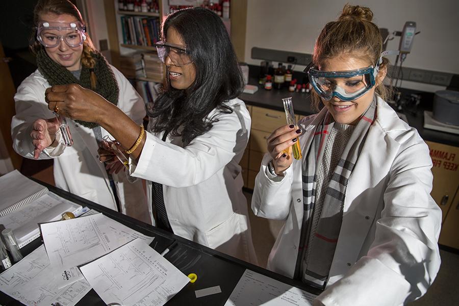 A faculty member works with students in the chemistry lab.