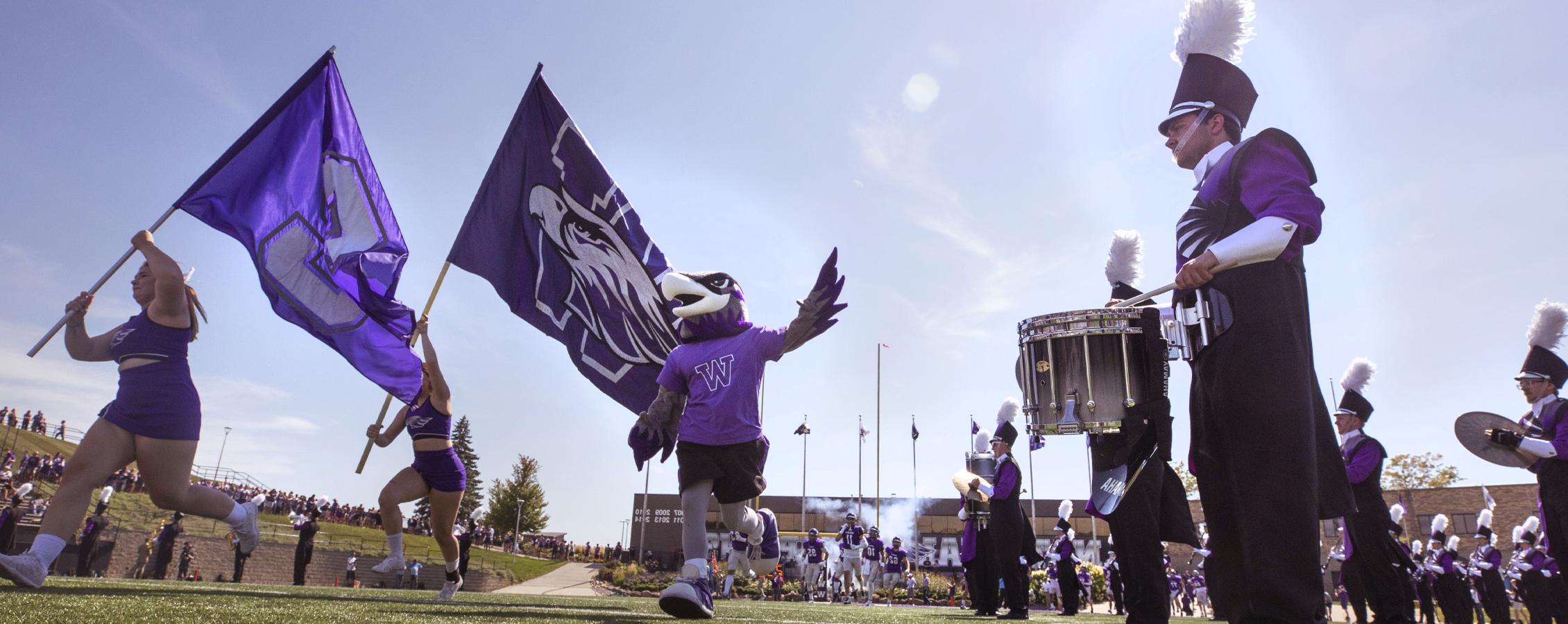 Willie Warhawk runs onto the Perkins Stadium field with the band.