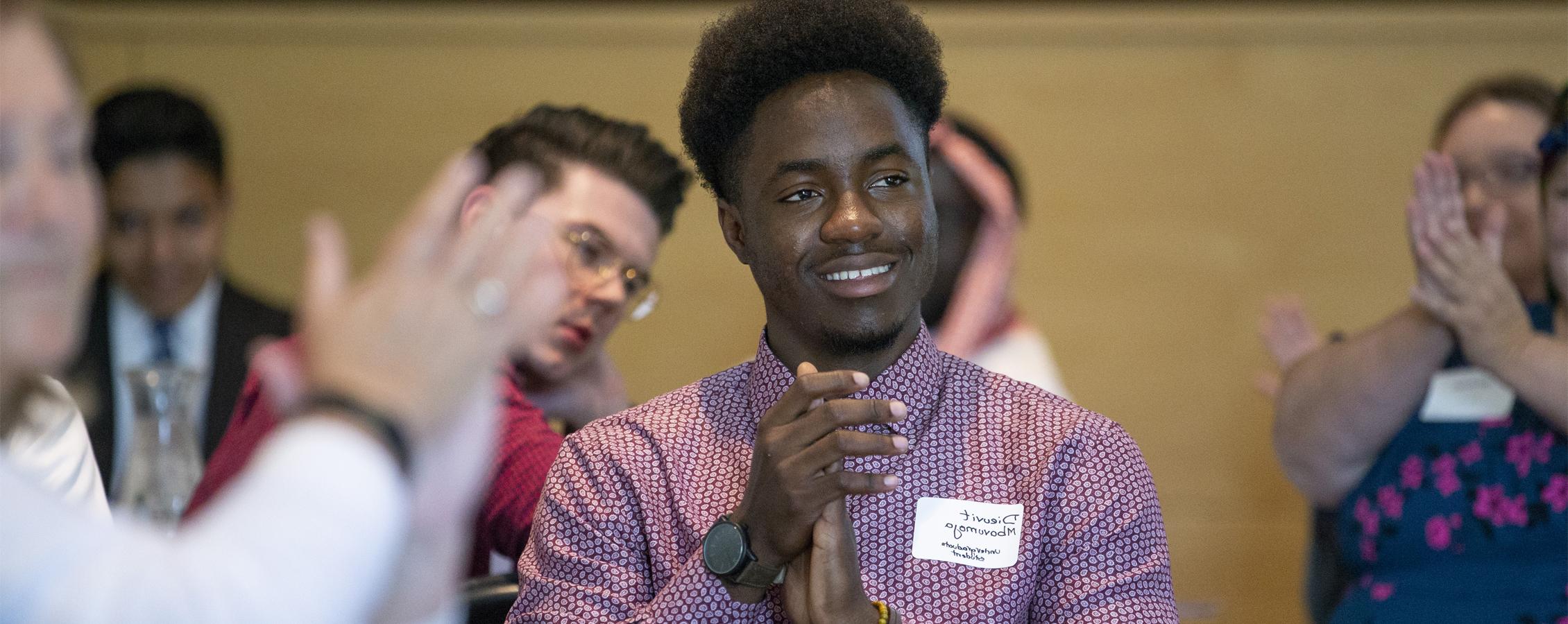 An international student claps during a campus event.