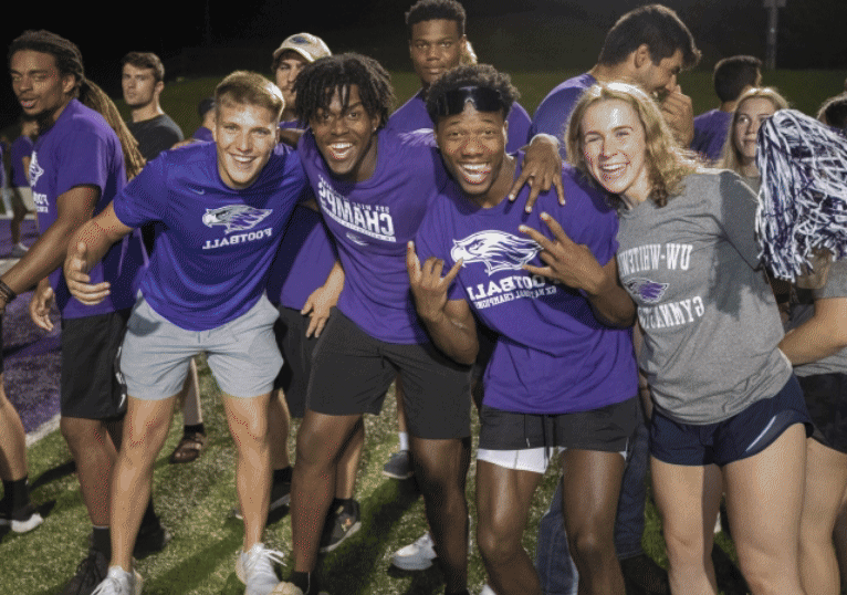 A group of students with their arms around each other smile at the camera.