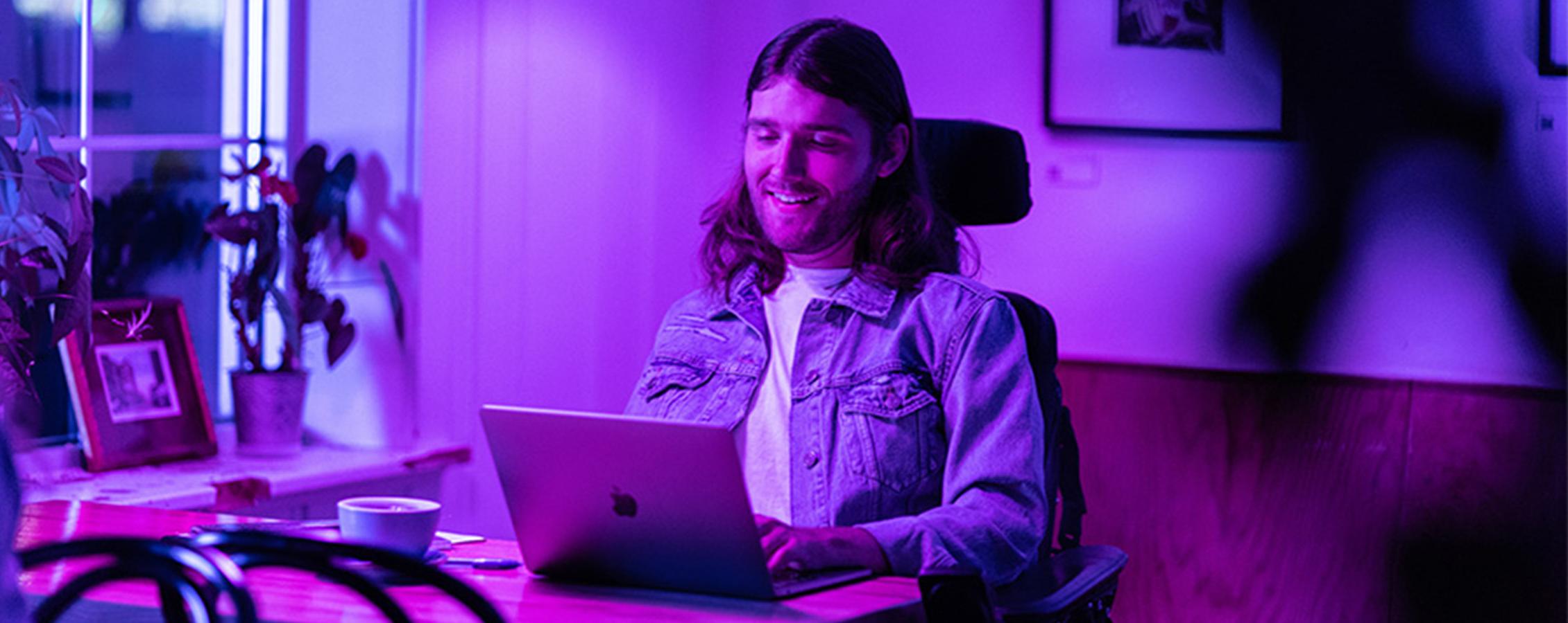 Young man in wheelchair working on laptop for online college  class