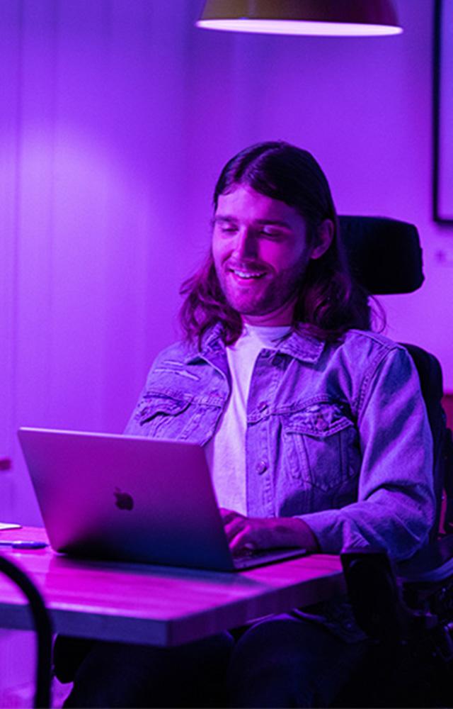 Young man in wheelchair working on laptop for online college  class